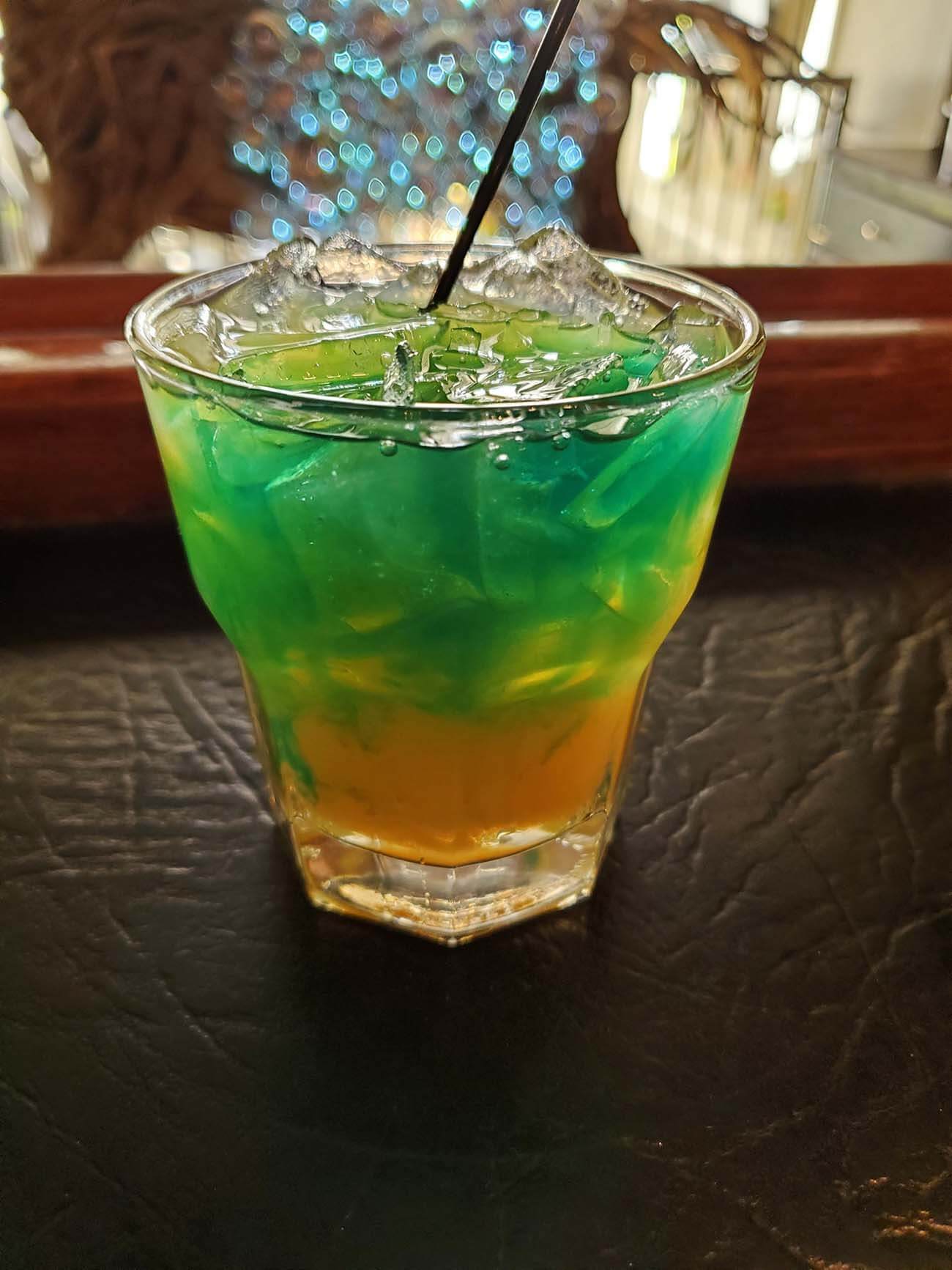 green and orange mixed cocktail in a glass